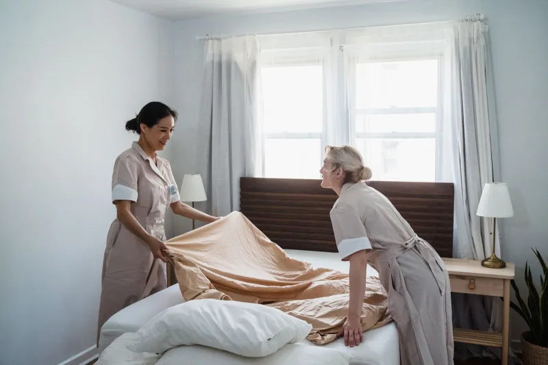 Two housekeepers making a bed with fresh linens